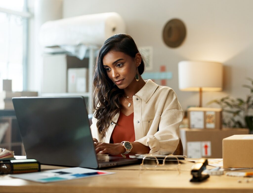 Woman, business and typing on laptop in office for research, feedback and supply chain for ecommerc